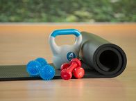 Verschiedene Trainingsgeräte: Igelball, Kettlebell, Hantel, Faszienrolle und Gymnastikmatte